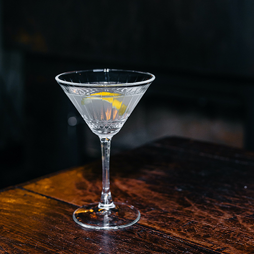 A Vesper Martini-- a wonderful cocktail but very boozy drink-- in a Martini glass on a wooden table, by Aleksandar Andreev via unsplash