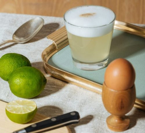 5. cocktail with a frothy finishm made with key lime juice with limes and eggs next to it, by getty images via unsplash