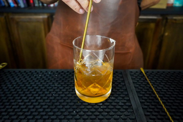 mixing old fashioned cocktail from scratch with ice cubes