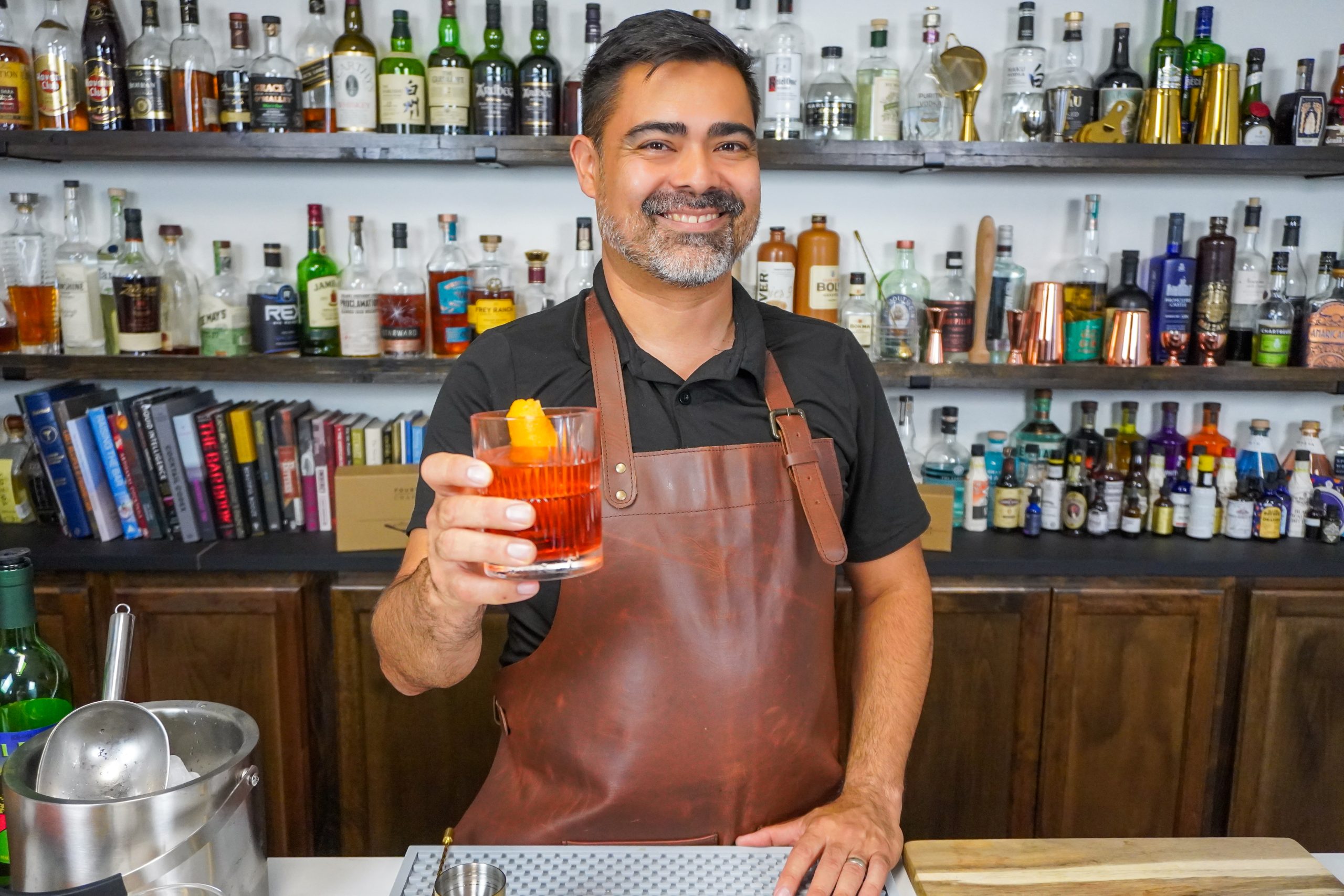 Bartender holding out a classic gin cocktail with a stronger flavor profile