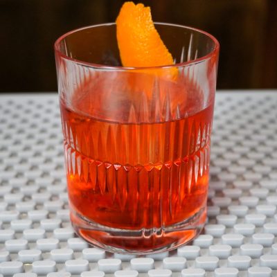 Negroni cocktail with 1 ounce sweet vermouth and 1 ounce gin in a lead-free crystal rocks glass with a larger capacity, with ice