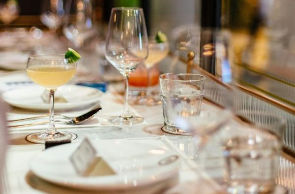 A restaurant table set with dining ware and cocktails and water glasses