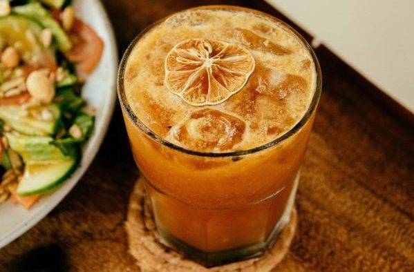 Cocktail next to a plate of food on a table