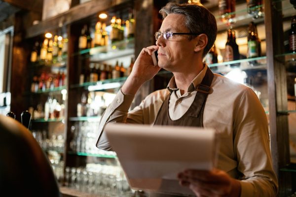Middle aged male server on the telephone in a commercial bar