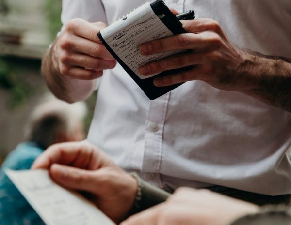 Server holding a order notebook while a guest points to the menu