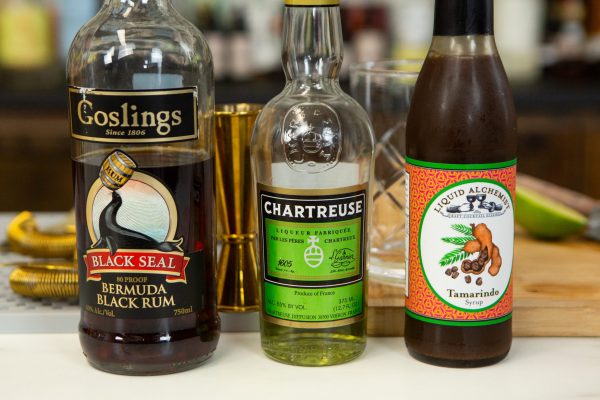 bottles of rum, Chartreuse, and tamarind syrup on a bar