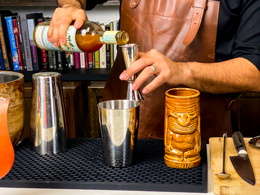 1. pouring two types of rum into cocktail jigger