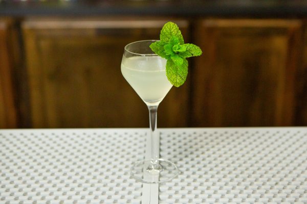 Cocktail in a chilled coupe glass with a sprig of mint as garnish