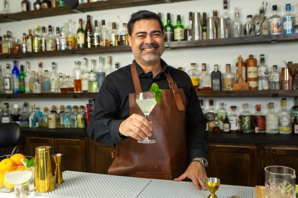 bartender holding a refreshing cocktail out to the audience and smiling