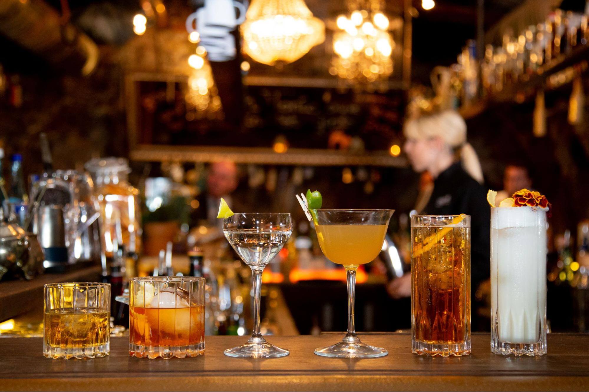An array of glassware displayed on a bar with an array of cocktails in them