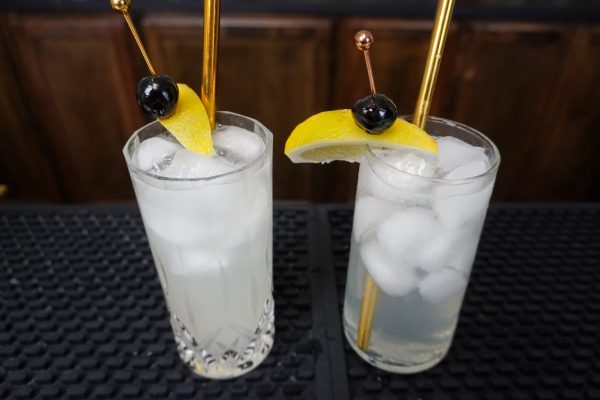 Two versions of the Tom Collins cocktail in tall glasses with gold straws