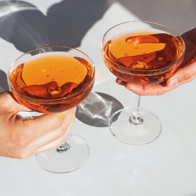 cocktails in coupe glasses being held by hands