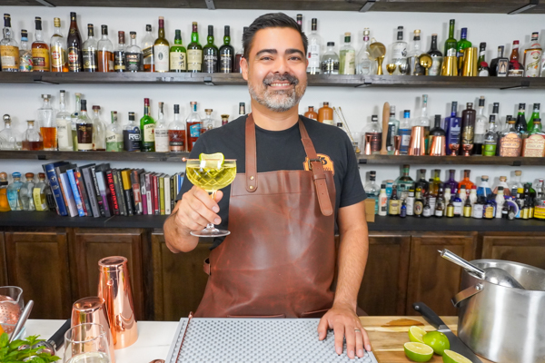 Bartender holding a Gimlet with cocktail glass garnish of lime wheel in a cocktail pub-5
