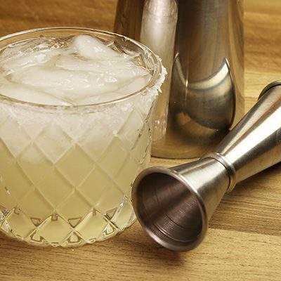 Margarita cocktail in rocks glass with cocktail shaker and alcohol jigger