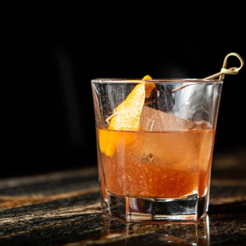 Photo of old fashioned cocktail in rocks glass with orange twist by paige ledford via unsplash