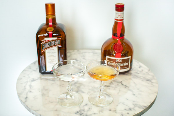 Cointreau and Grand Marnier bottles with liquor in coupe glasses