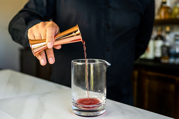 Наливание спирта в стакан для смешивания с японским джиггером