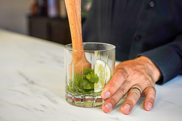 Muddling fresh mint in a cocktail