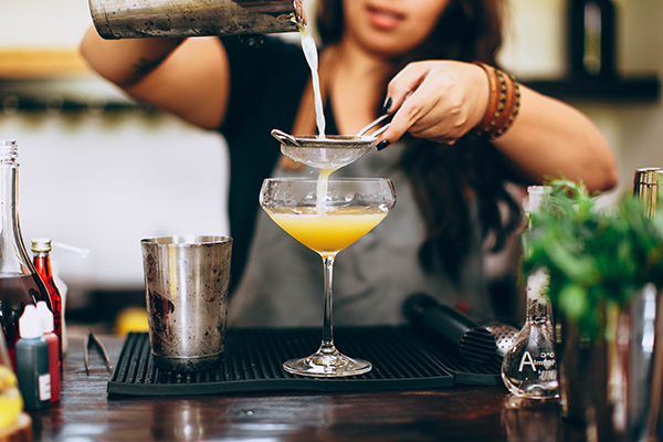 Bartender pouring a cocktail by helena lopes via unsplash.com