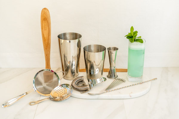 14 piece cocktail set of durable option essential bar tools including a Boston shaker, affordable muddler, and separate strainer next to a Collins glass