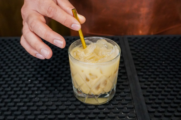 Putting a straw into the white russians drink with Kahlúa original, your favorite cream or milk, and vodka for a decadent drink