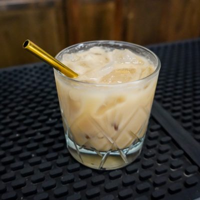 White Russian cocktail hour drink on a bar with a gold straw