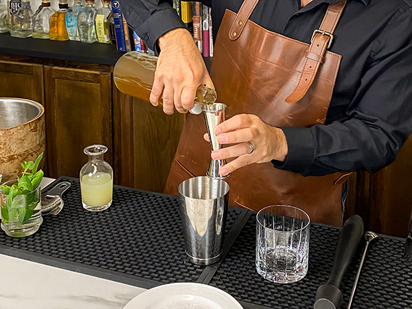 Pouring non-alcoholic rum into cocktail jigger for a mojito mocktail syrup