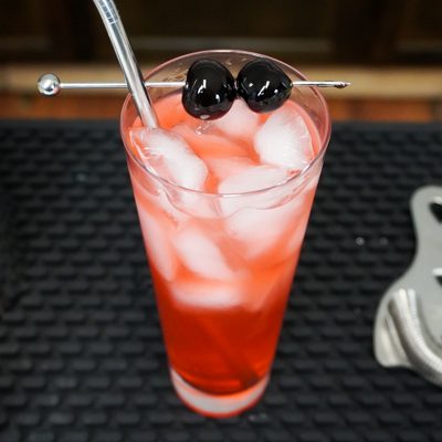 Shirley Temple pink drink in a tall glass with cocktail cherry garnish