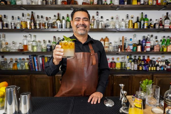 5. Bartender holding an exotic rum drink in a double rocks glass with a lime wheel, branch of mint, and 1/2 ounce rich simple syrup