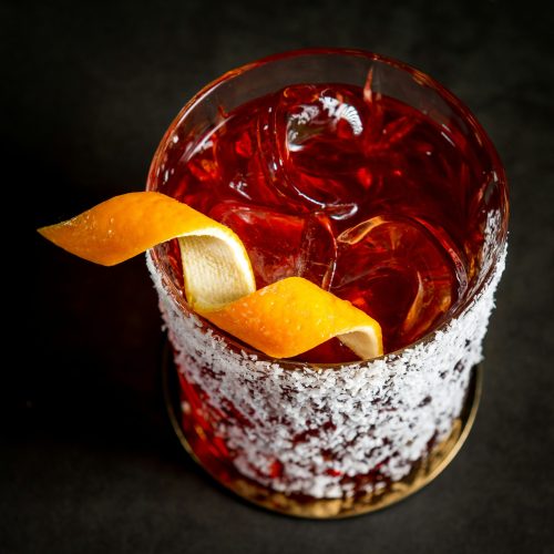 Rocks glass of amaro with ice, with sugar rim and an orange twist