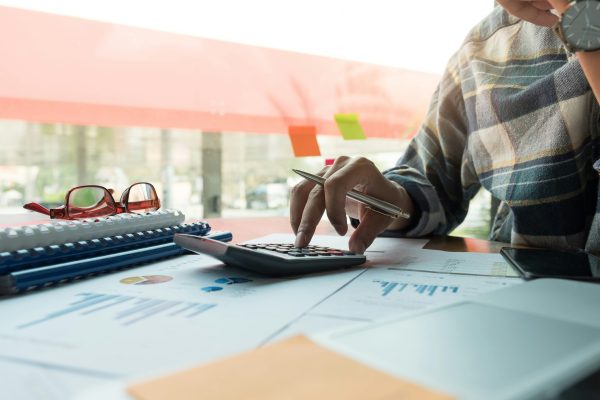 hand on a calculator, calculating current inventory level of the bar and extra inventory needed