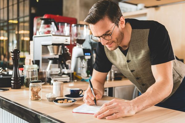 bartender using a customizer par inventory sheet at a coffee bar countertop