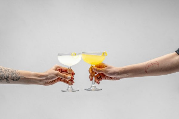 two hands clinking cocktail glasses for a creative date night idea of making your own cocktails