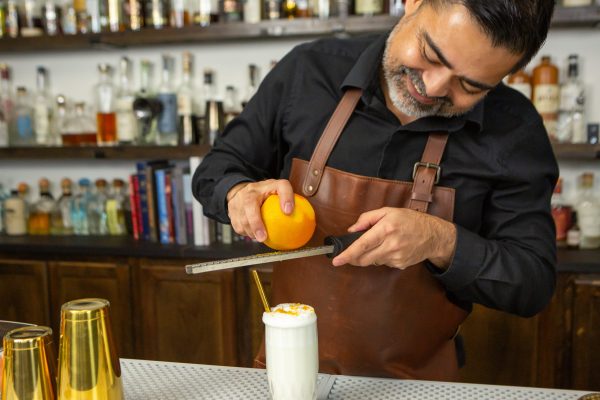 Bartender zesting an orange over a cocktail