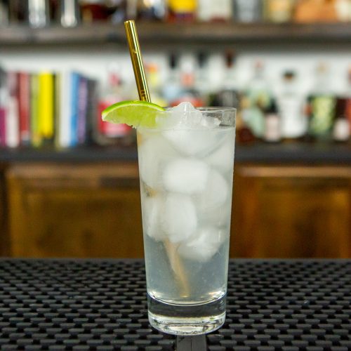 Ranch water cocktail on a bar with a gold straw and lime slice