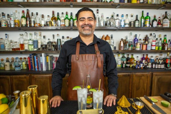 bartender standing at his bar with two mixed drinks