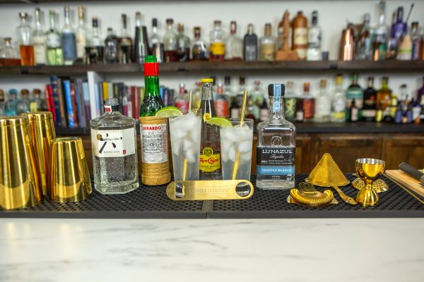 two versions of the Ranch Water cocktail, surrounded by ingredients and bar tools on a bar