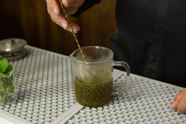 a cup of hot tea being stirred with a bar spoon